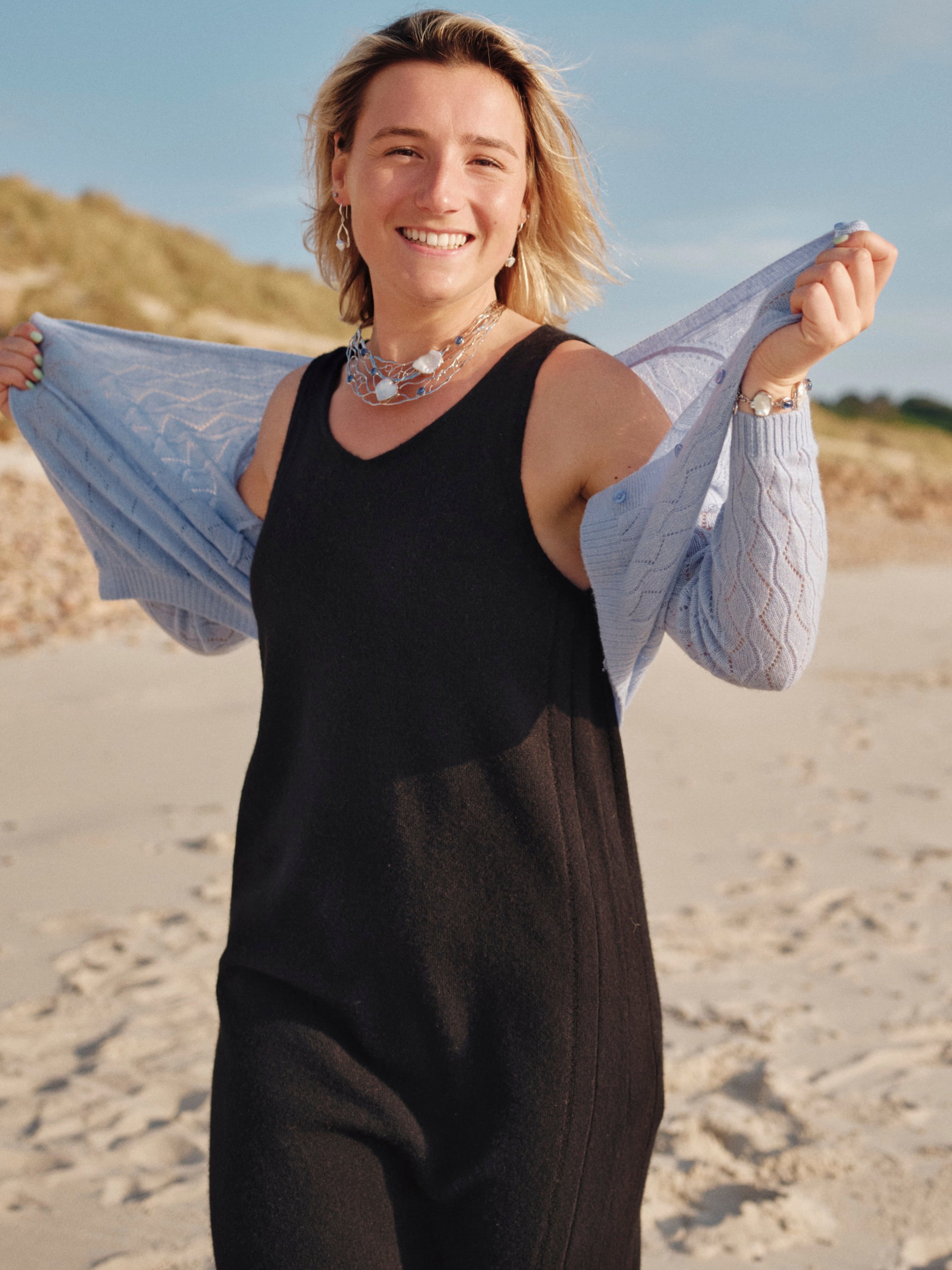 Model outdoors wearing a black v-neck cashmere midi dress