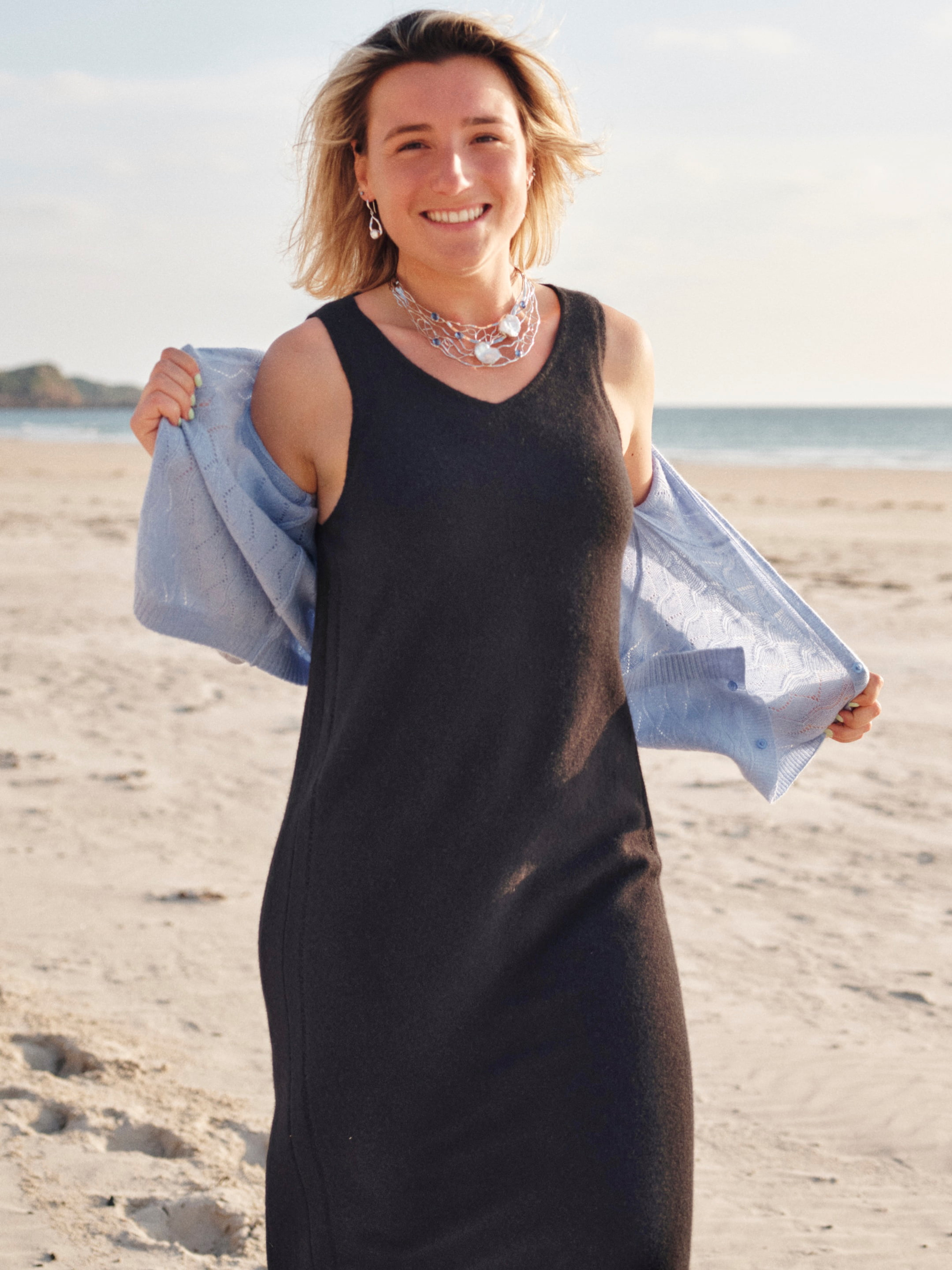 Model outdoors wearing a black v-neck cashmere midi dress
