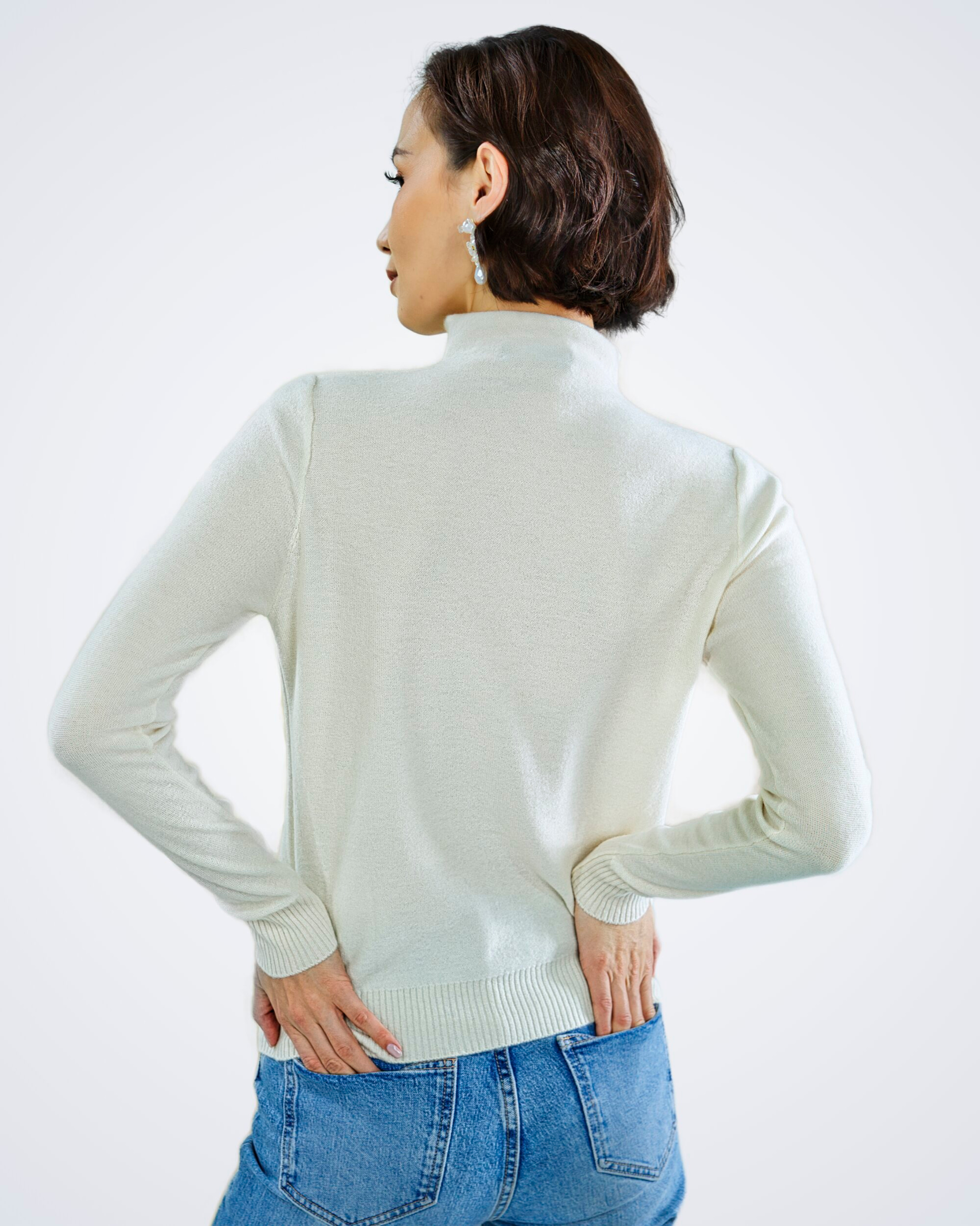 Unur model wearing a white high-neck patterned cashmere lightweight sweater, back view