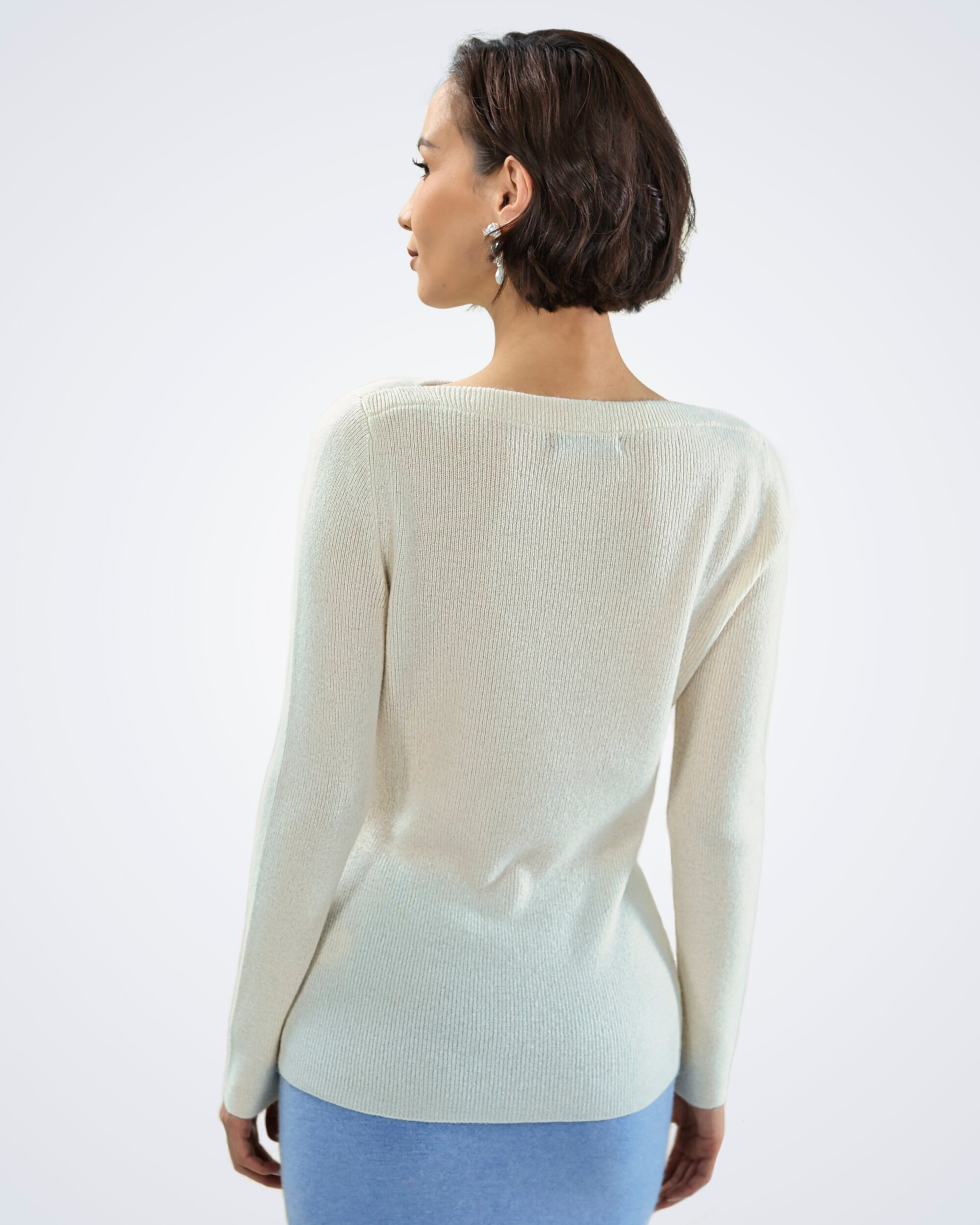 Unur model wearing a white boat neck ribbed cashmere jumper, rear view