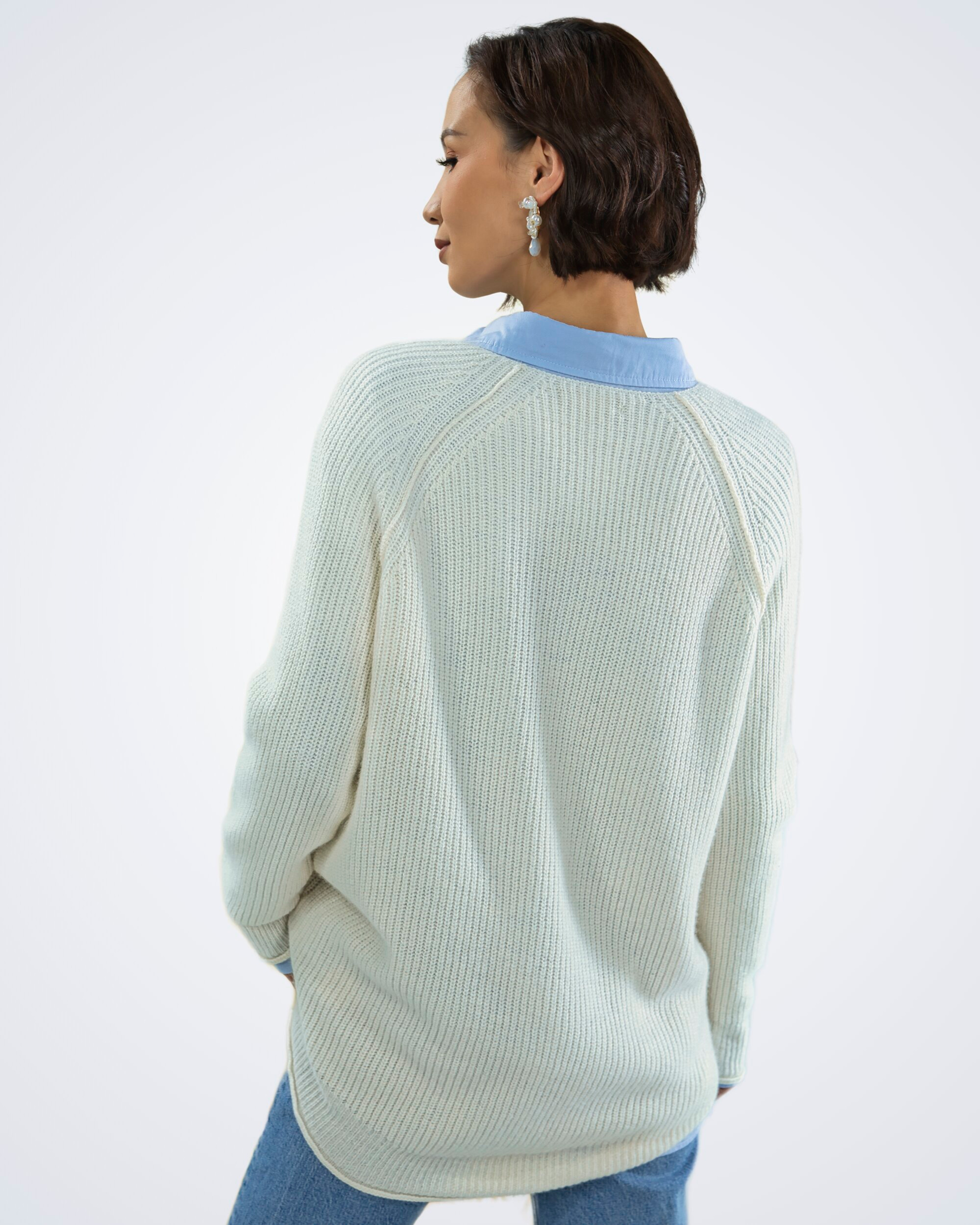 Unur model wearing a white V-neck ribbed cashmere jumper with exposed seams, rear view