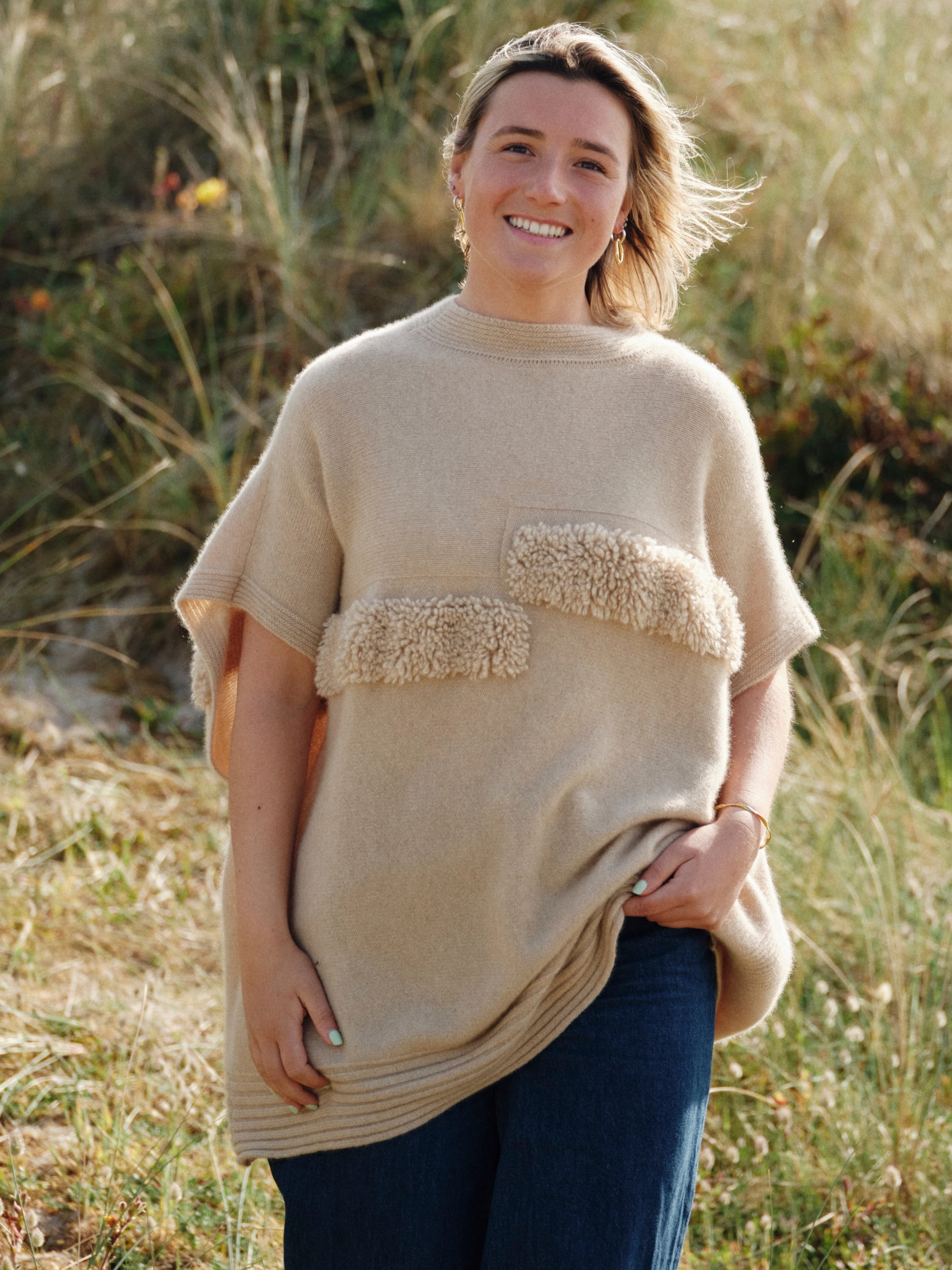 Unur model wearing a natural beige ribbed cashmere poncho with faux fur trim