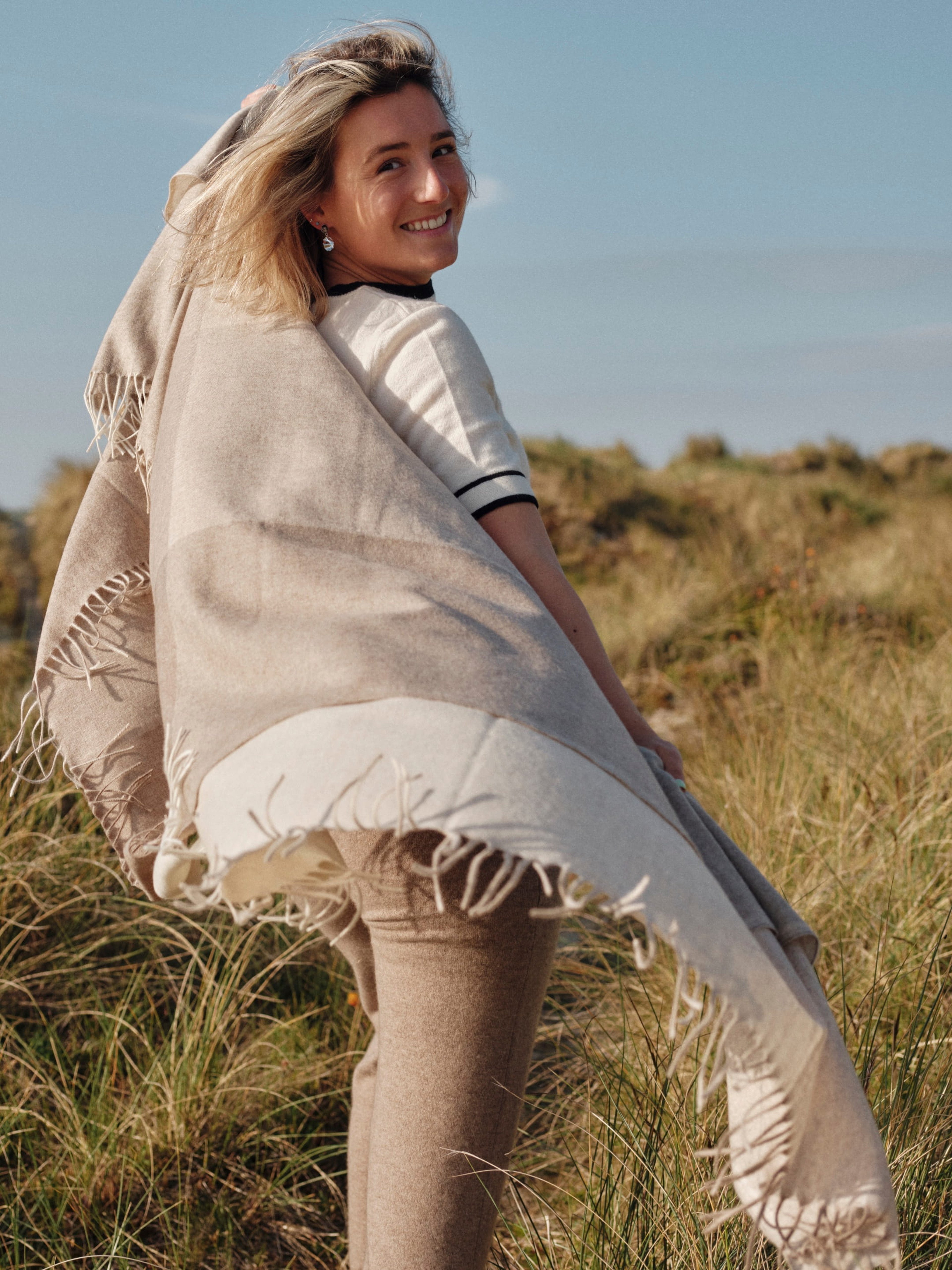 Model outdoors wearing a cashmere check pattern wrap shawl in natural brown tones