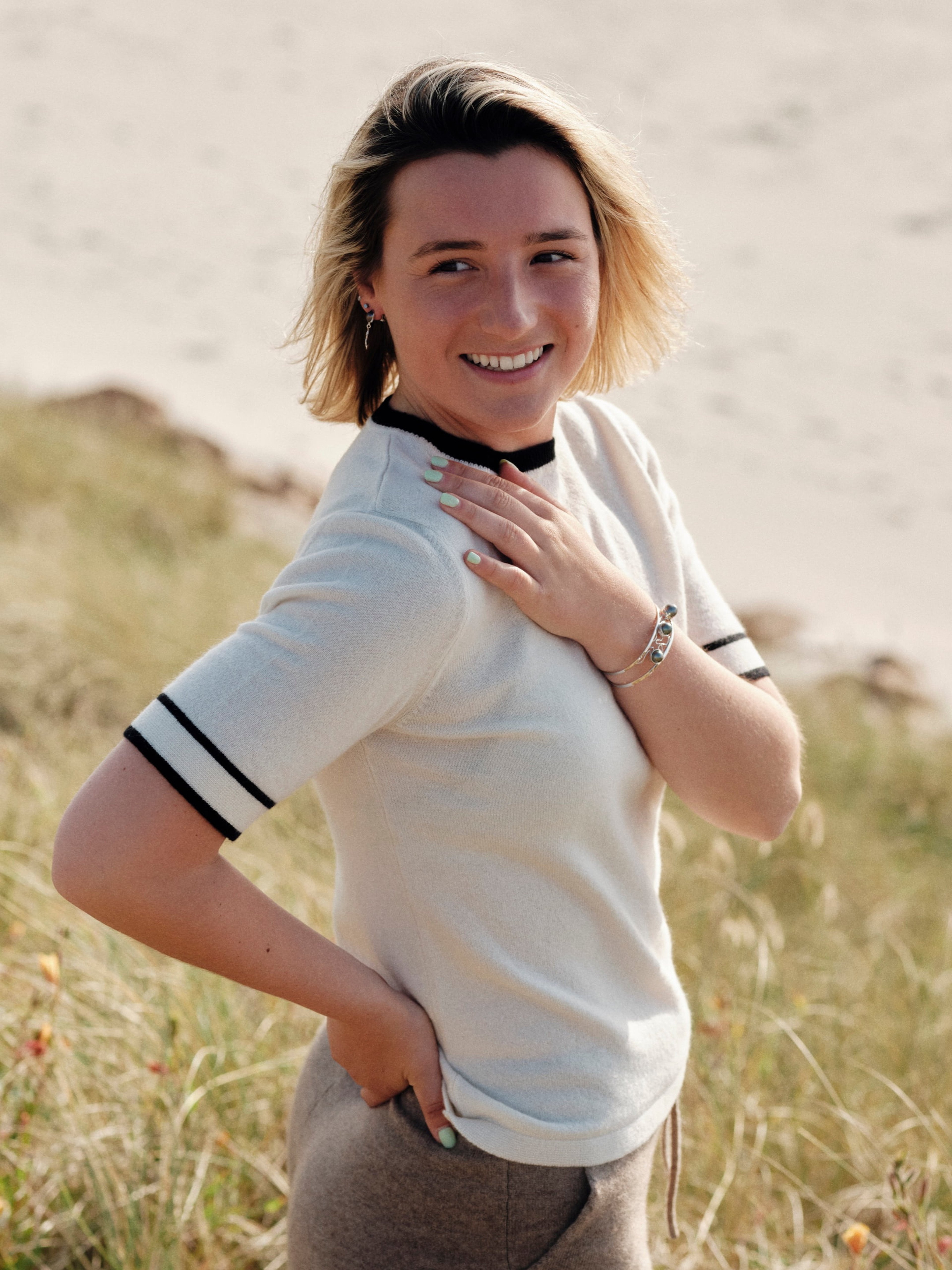 Model outdoors wearing a white round neck cashmere t-shirt with black contrast trim