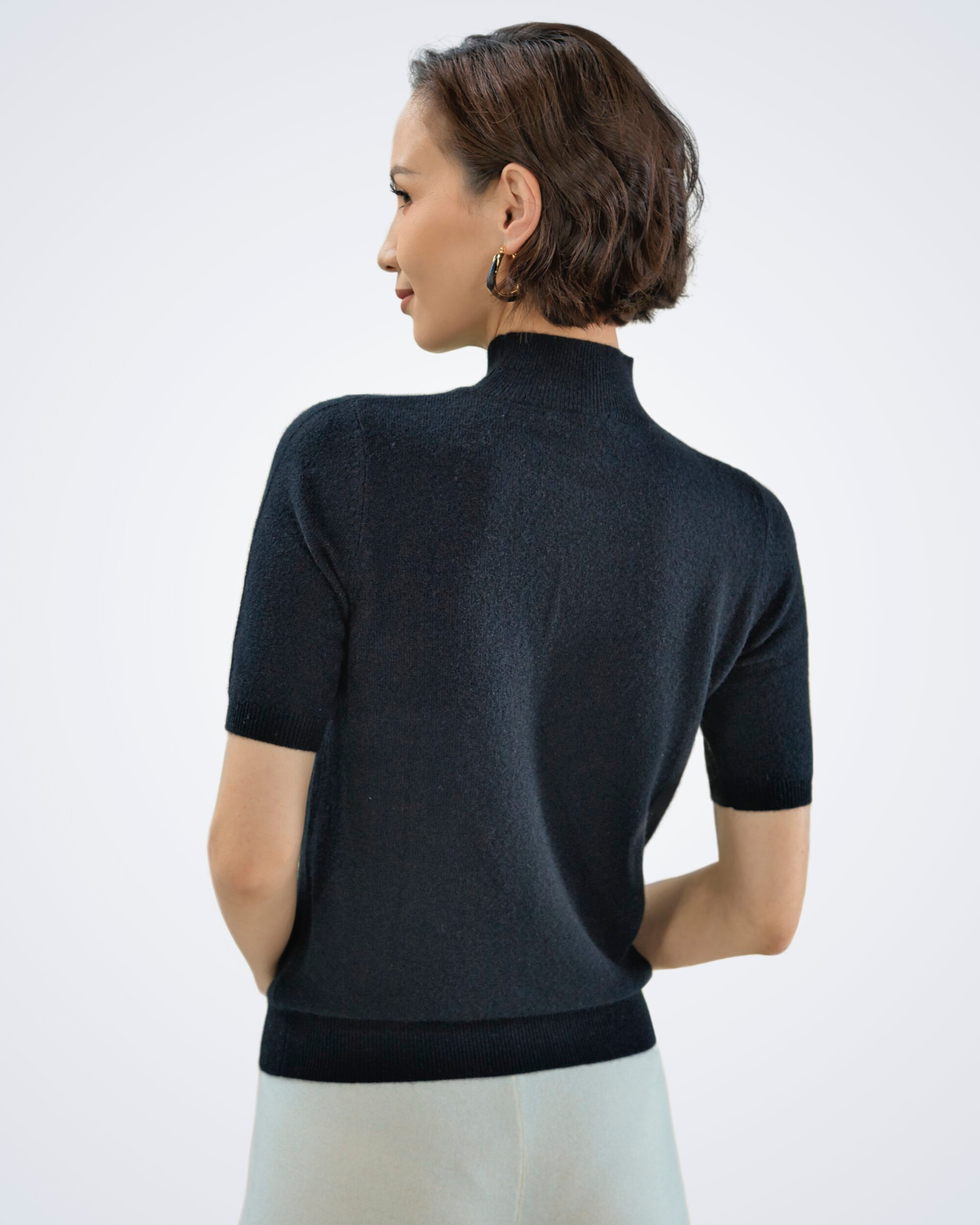 Unur model wearing a black high-neck cashmere t-shirt, rear view