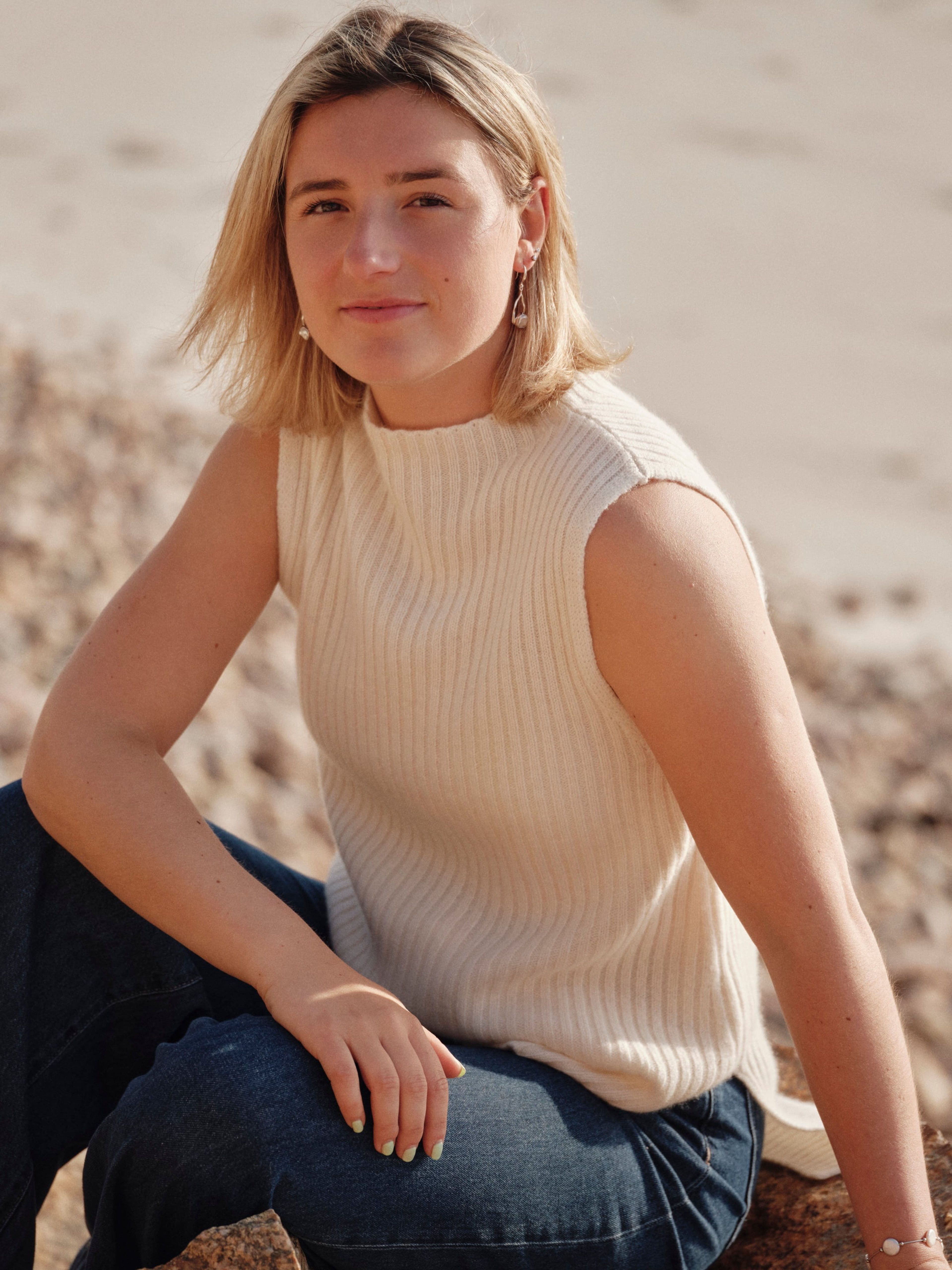 Model outdoors wearing a white ribbed cashmere vest