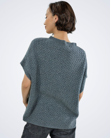 Woman wearing a grey luxury cable knit cashmere vest, rear view