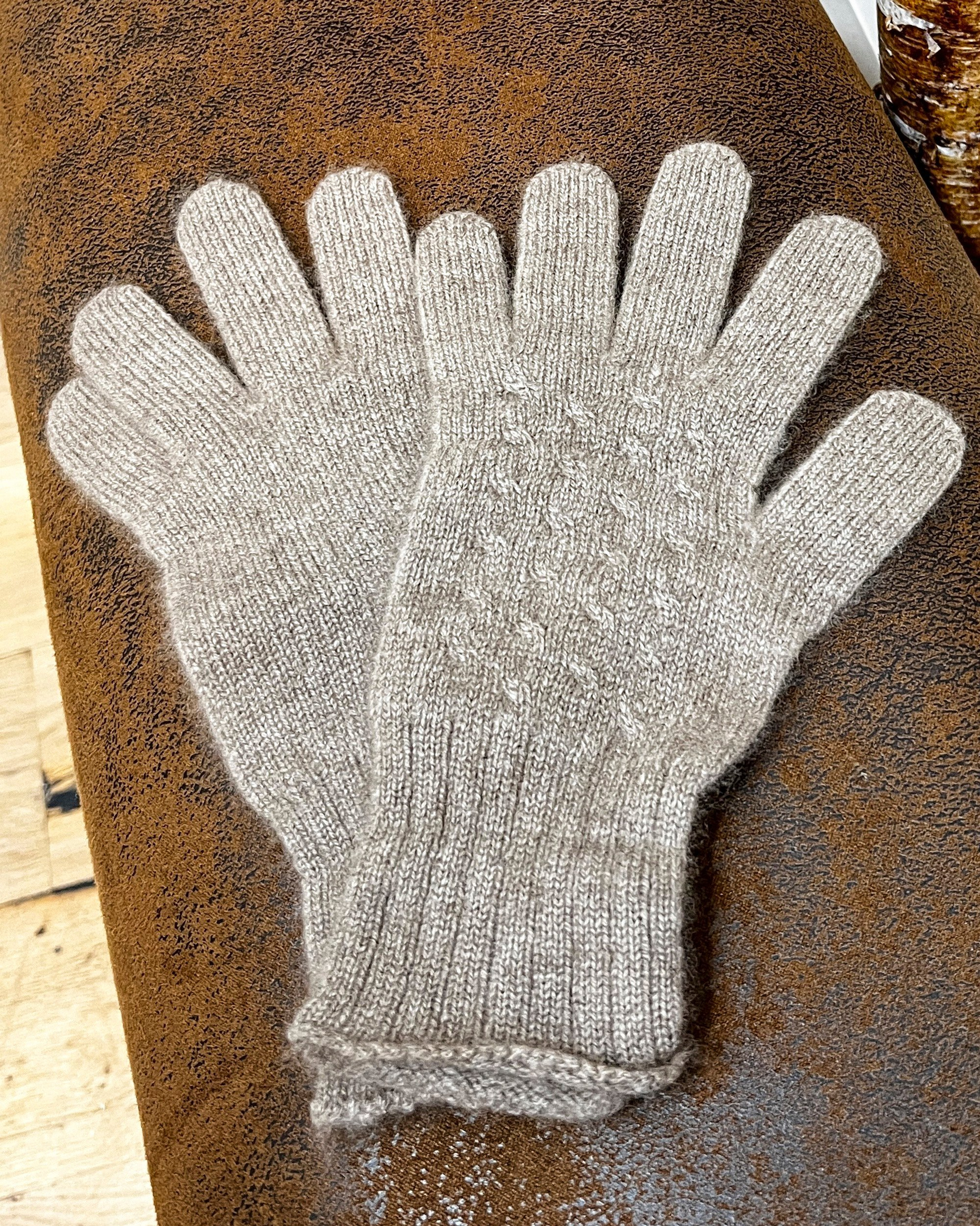 Natural brown cashmere gloves on neutral background, flat view