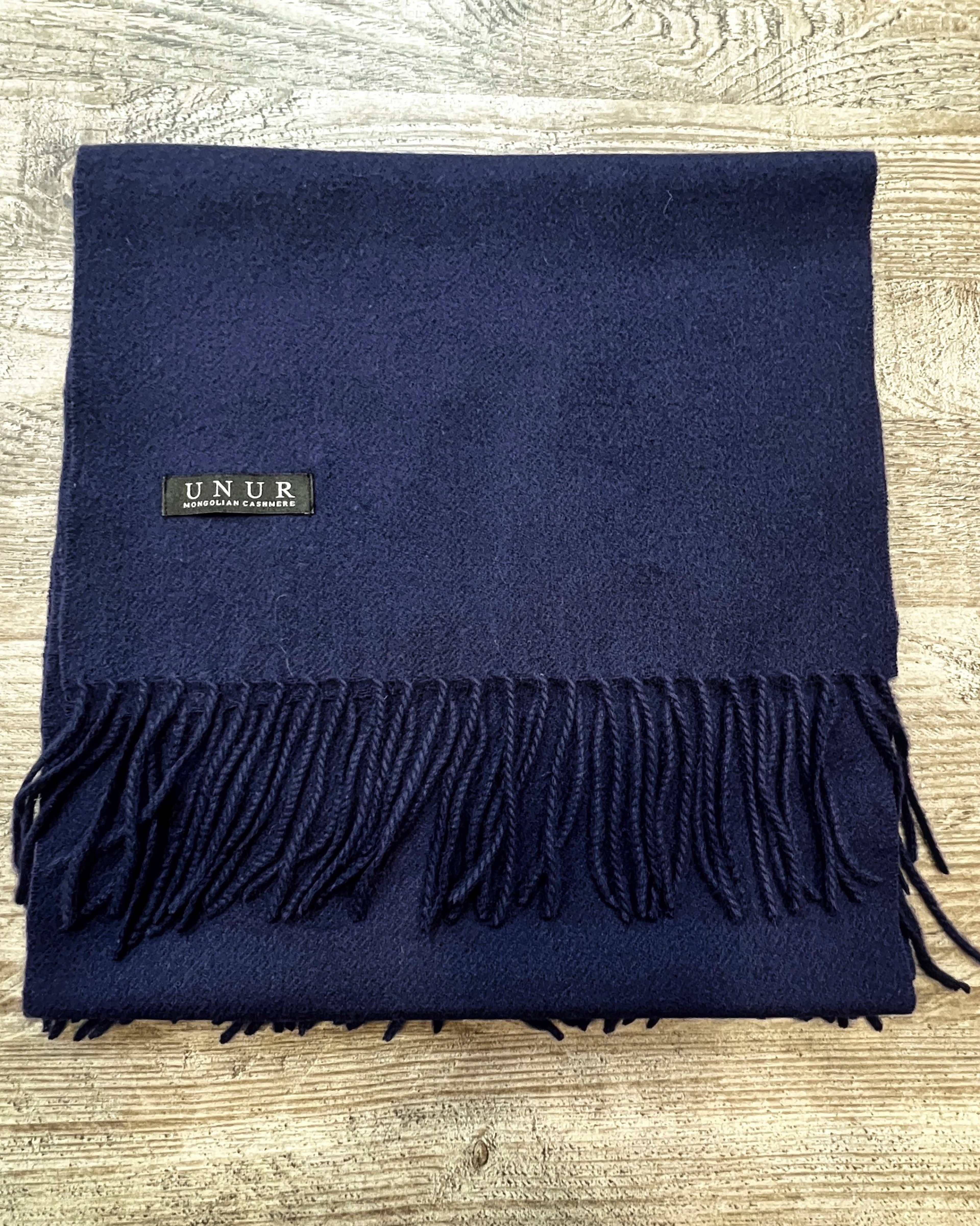 Navy blue cashmere scarf on neutral background, flat view