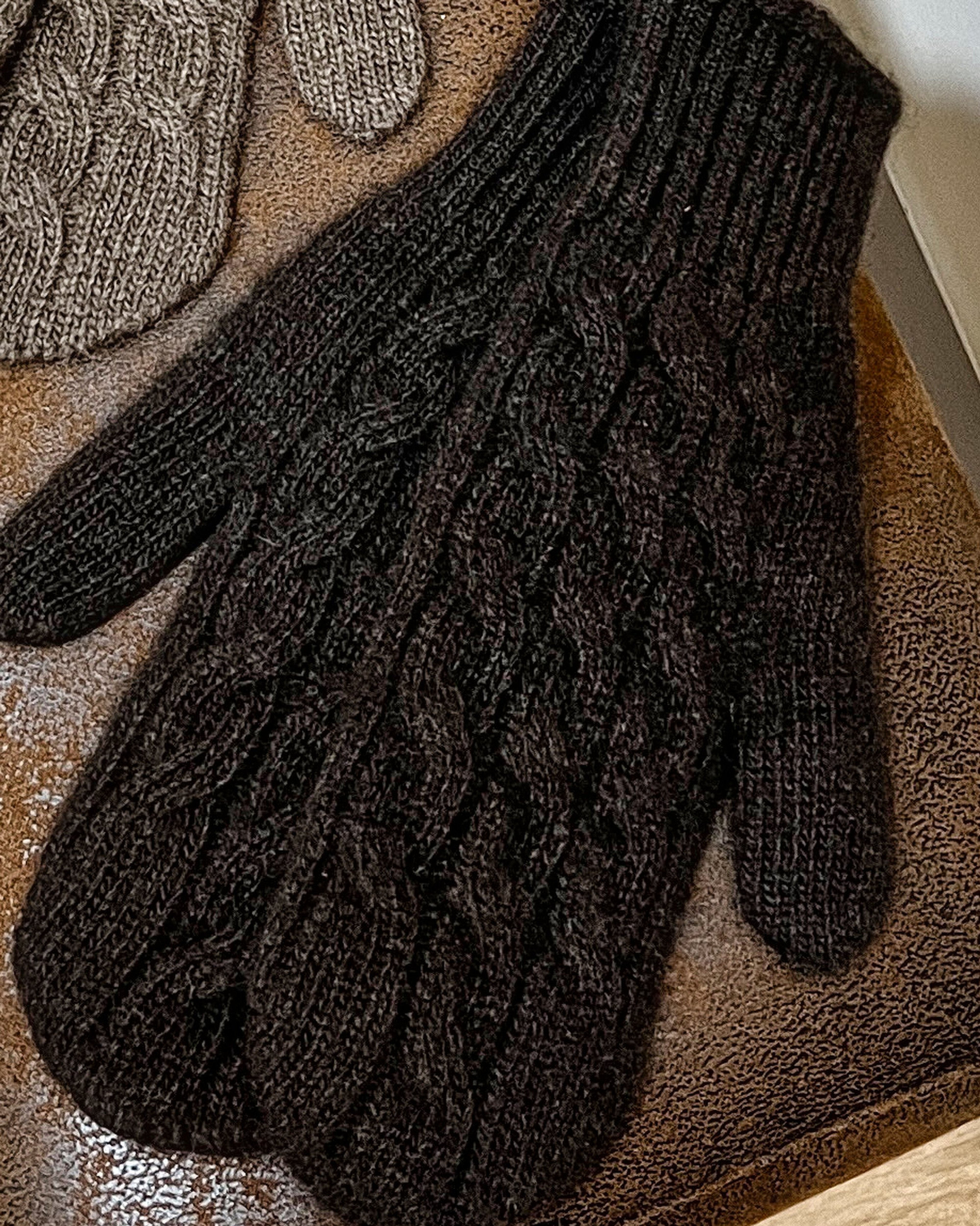 Dark brown yak wool mitten gloves on neutral background, flat view