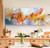 A close-up detail of a vibrant horizontal abstract painting. The composition is energetic and light-filled, dominated by warm washes of golden yellow, burnt orange, peach and ochre that bloom across the center. Contrasting soft sky blue and teal washes fill the background, especially in the lower left and upper center. Playful, looping ribbons of bubblegum pink and coral are scattered across the surface. Small bursts of lime green and chartreuse appear on the right edge. The texture is layered and airy with visible dry-brush, paint drips, and impasto swirls, creating a joyful, garden-like, celebratory atmosphere.