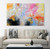 Colorful large abstract painting in bright pink, golden yellow, warm orange and sky blue with soft white and black, layered expressive brushwork