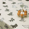 Wipe Clean Tablecloth - Acrylic Coated-  Loneta: Two Tone Chickens. Pictured on a table with a basket of eggs.