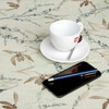 Digital : Verdara. Wipe Clean Tablecloth pictured on a table with a cup, saucer and phone