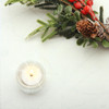 Wipe Clean Tablecloth - Blaze: Silver Sprig. Pictured on a table with a votive tealight candle and seasonal greenery.