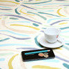 Acrylic Coated Tablecloth - Living:  Brush Strokes - pictured with a cup and saucer, 'phone, pen and coins.
