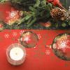 Navarra Festive wipe clean acrylic oilcloth fabric pictured with a votive tealight candle and seasonal greenery.