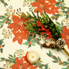 Navarra Christmas Flowers wipe clean acrylic oilcloth fabric pictured with a votive tealight candle and seasonal greenery.