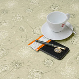 Mirha Dandelion wipe clean acrylic coated tablecloth. Pictured with a cup,saucer, 'phone and pen - to show scale.