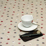 Acrylic Coated Tablecloth - Living: Strawberry Wine - pictured with a phone, pen, cup and saucer.