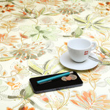 Navarra: Sandra.  Acrylic Coated Tablecloth, pictured on a table with a cup and saucer, 'phone, pen and coins.
