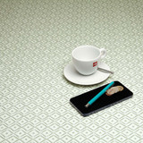 Navarra: Jewel.  Acrylic Coated Tablecloth, pictured on a table with a cup and saucer, 'phone, pen and coins.