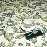 Living Simone Blue Wipe Clean Tablecloth. Pictured with a cup and saucer, 'phone, pen and coins.