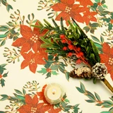 Navarra Christmas Flowers wipe clean acrylic oilcloth fabric pictured with a votive tealight candle and seasonal greenery.