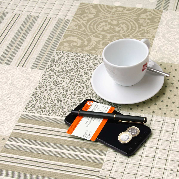 Wipe Clean Tablecloth Fabric. Mirha: Patchwork - Pictured with cup,saucer, phone and pen.
