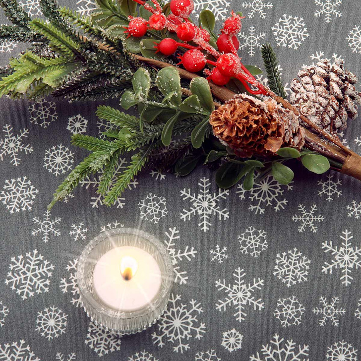 Living: Snowflake Grey Acrylic Coated Wipe Clean Christmas Fabric. Pictured with a votive candle tealight and seasonal greenery