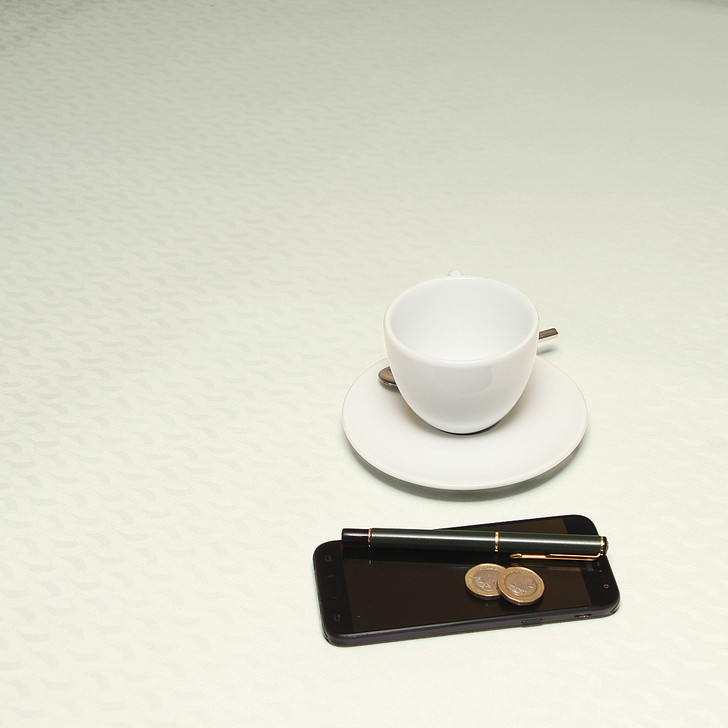Acrylic coated tablecloth: Murcia Munch. Pictured with a cup and saucer, 'phone, pen and coins