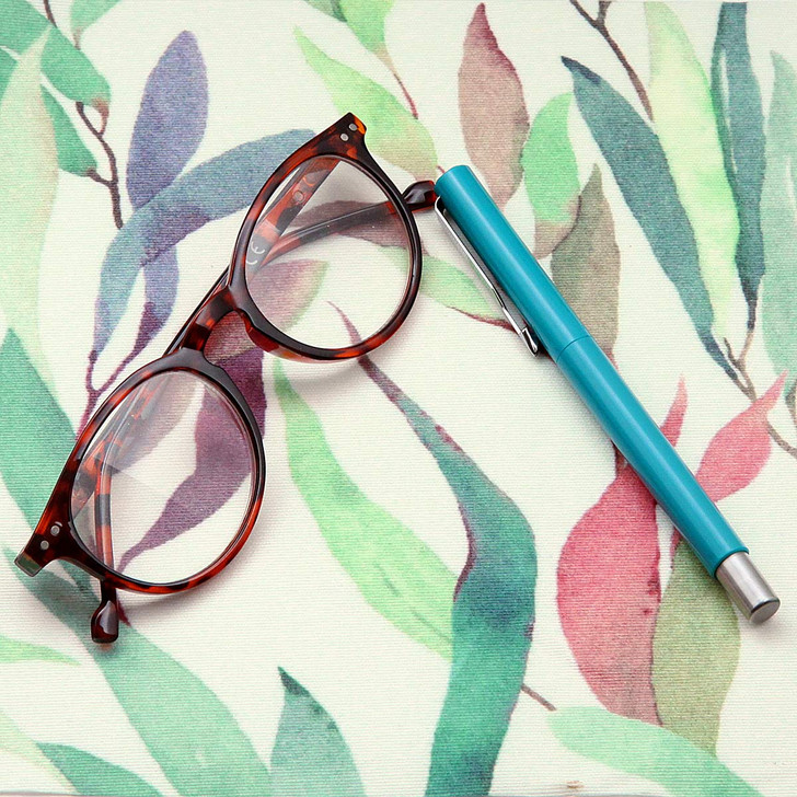 Wipe Clean Tablecloth - Digital Fronds. Pictured on a table with a pair of glasses and a pen