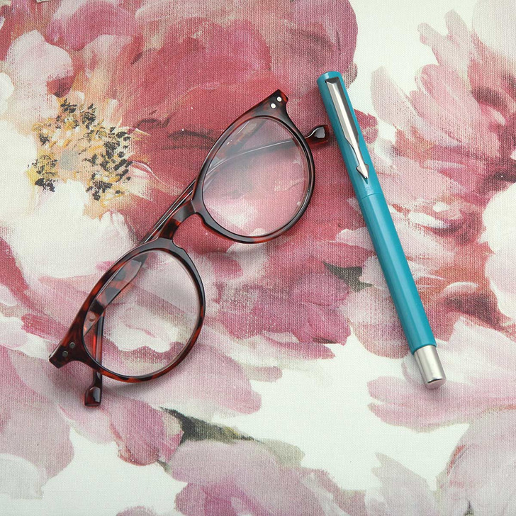 Wipe Clean Tablecloth - Digital Peony. Pictured with a pair of glasses and a pen.