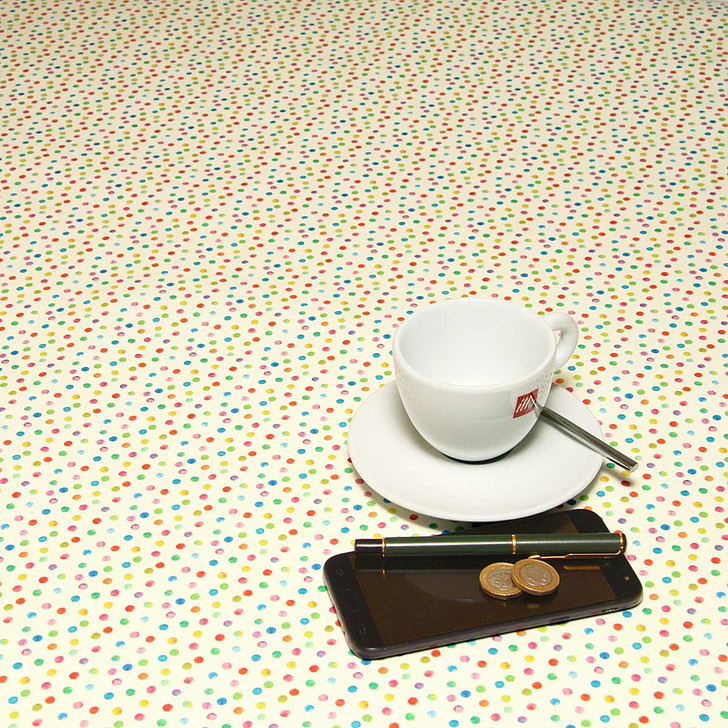 Navarra: Lina.  Acrylic Coated Tablecloth, pictured on a table with a cup and saucer,  'phone, pen and coins.