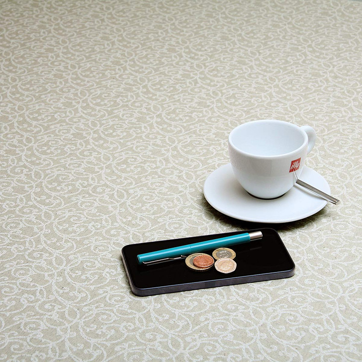 Wipe Clean Tablecloth - Mirha Wollaton - pictured with a cup, saucer, phone, pen and coins.