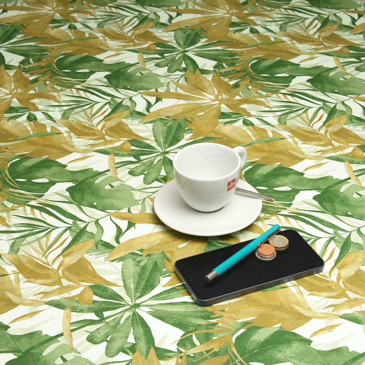 Living Tropical Green: Wipe Clean Tablecloth. Pictured with a cup and saucer, 'phone, pen and coins.