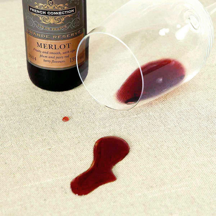 Wipe Clean Tablecloth - Mirha Natural - shown with a spill of red wine beading on the surface.