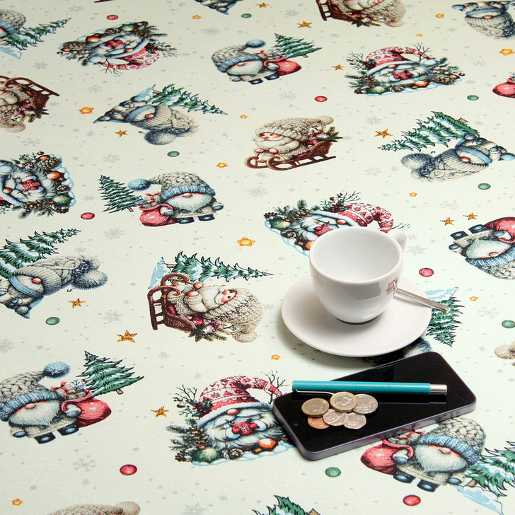 Wipe Clean Christmas Tablecloth. Living Tinker Cream. Pictured with a cup and saucer, 'phone, pan and coins.