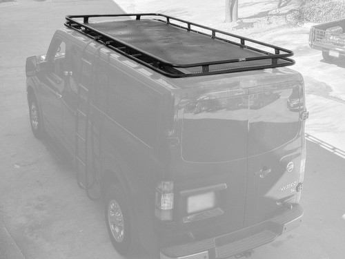 A black-colored Nissan NV van with a black powder coated Weekender Roof Rack from Aluminess Products.