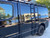 A gloss black Nissan NV van with a powder coated black side ladder, surf board mount pole, surf hooks, and roof rack from Aluminess Products.