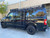 A gloss black Nissan NV van with a powder coated black side ladder, surf board mount pole, surf hooks, and roof rack from Aluminess Products.