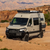 Beige Mercedes Sprinter van outfitted with several off-road accessories, parked near open canyons.