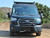A black Ford Transit van equipped with a Baja style front winch bumper.