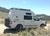 A gloss white Nissan NV van with an off-road rear bumper and accessories from Aluminess Products.