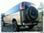 A tan-colored Chevy Express van with a driver side rear door tire rack from Aluminess Products.
