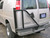 A tan-colored Chevy Express van with a driver side rear door tire rack from Aluminess Products.