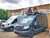 A Black Ford Transit van parked on the street, equipped with a touring roof rack from Aluminess Products.
