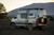 Side view of an beige Mercedes Sprinter van featuring an Aluminess Explorer Roof Rack and Side Ladders.