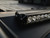 Close-up view of the Recon Rack Light Bar Bracket from Aluminess, securely mounted on the roof of a Transit van.