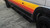 Full side view of a van with Promaster Recon Side Steps on a gravel surface.